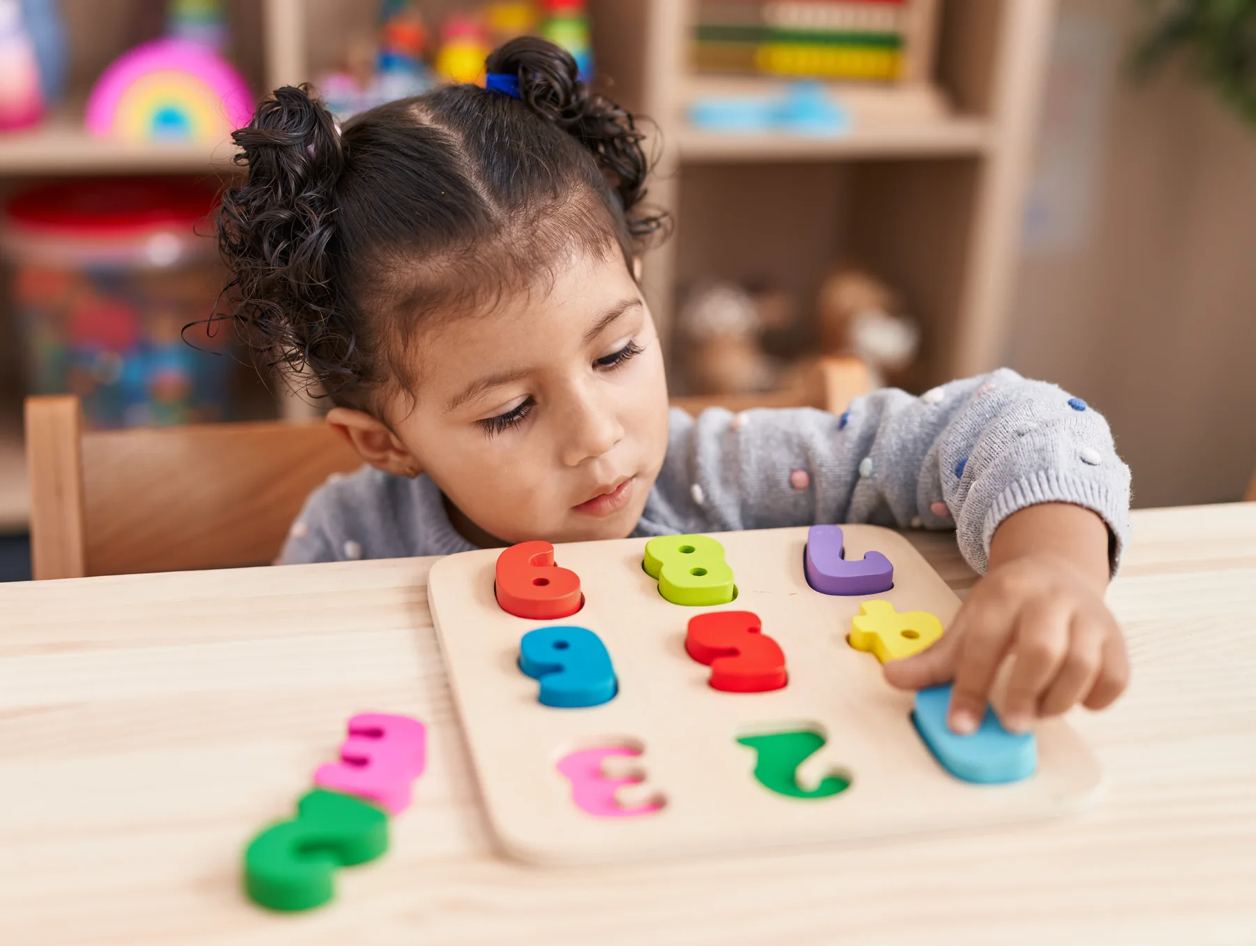 Child concentrating on a wooden number puzzle