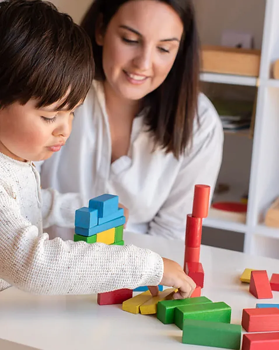 Teacher guiding a child stacking wooden blocks